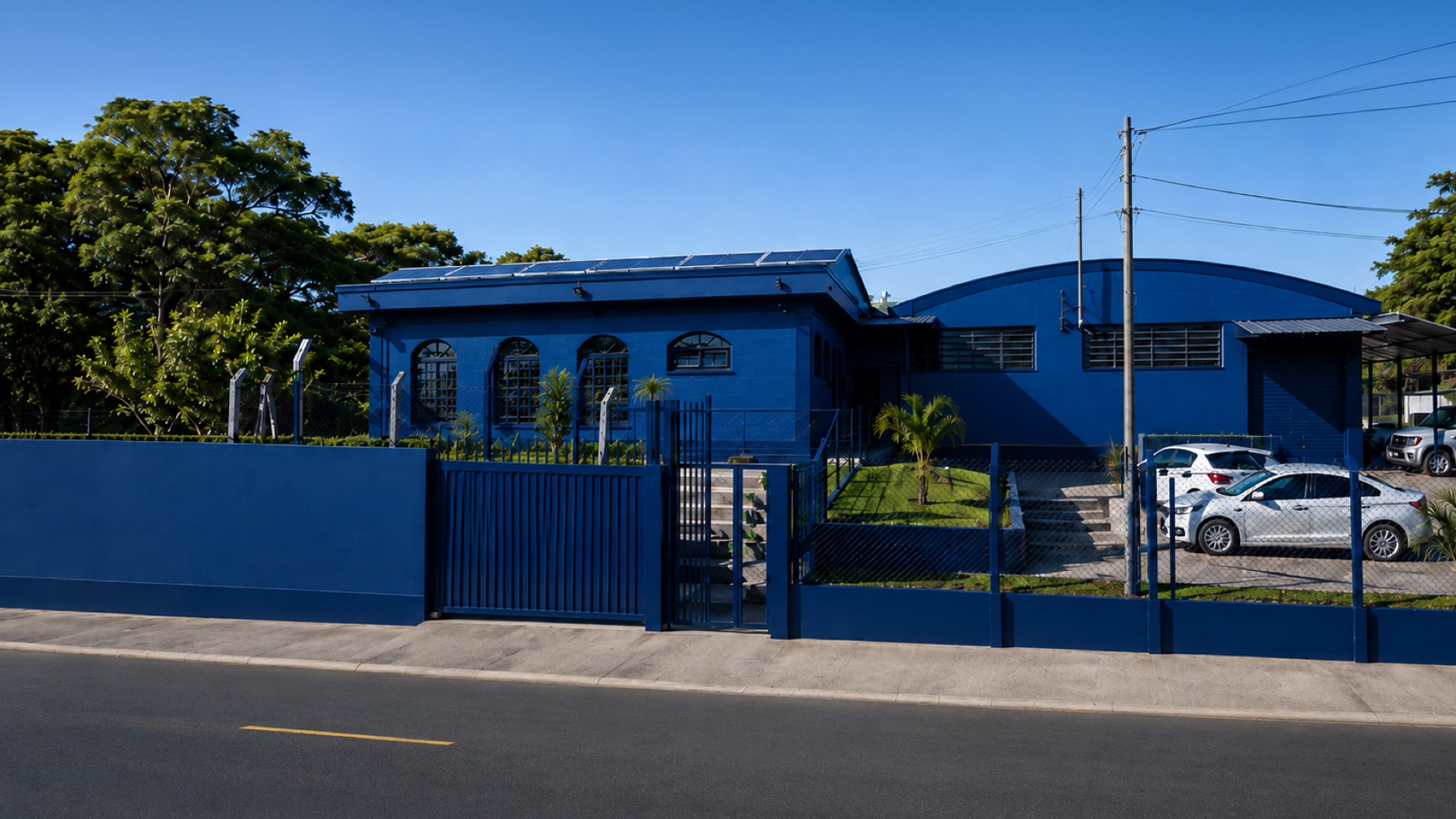 Fachada da sede da Alumax Distribuidora em São Simão–SP · prédio azul com painéis solares, vista da rua